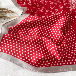 Détail d'un foulard en soie rouge à pois et cachemire montrant la texture brillante