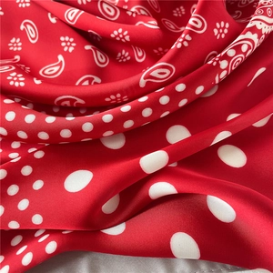 Gros plan d'un foulard en soie rouge avec motifs paisley et pois montrant sa texture lisse