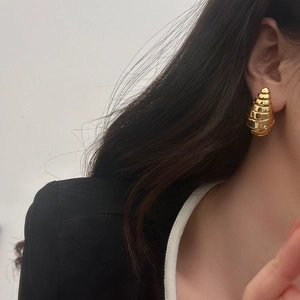 Vue détaillée de grandes boucles d'oreilles spirales dorées portées par un mannequin