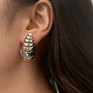 Gros plan de boucles d'oreilles gouttes creuses argentées au fini métallique brillant