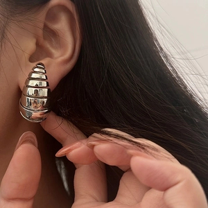 Gros plan d'un mannequin portant des boucles d'oreilles spirales creuses en argent poli