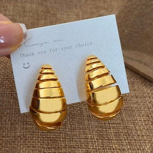 Gros plan sur des boucles d'oreilles dorées en spirale conique sur leur support