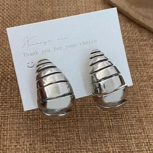 Gros plan sur boucles d'oreilles spirales argentées avec rainures texturées