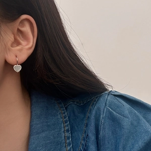 Gros plan de boucles d'oreilles cœur en argent avec nacre et cristaux étincelants