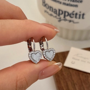 Gros plan de boucles d'oreilles cœur avec pavé de zircons et nacre sur fermoirs en forme de D