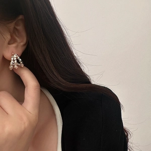 Close-up of golden geometric faceted cluster earrings worn on a model's ear