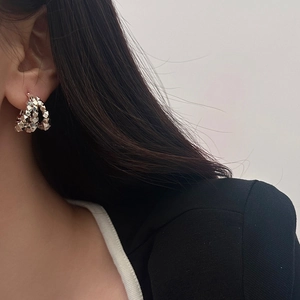 Detail of silver geometric textured earrings worn by a model in a modern style