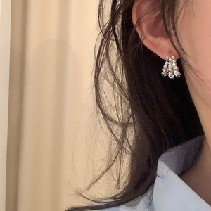 Macro shot of a model wearing tiered silver geometric bead cluster earrings