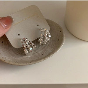 Macro shot of silver crushed metal bead earrings displayed on a grey textured card holder