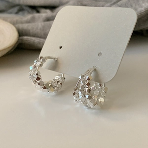 Detail of silver geometric hoop earrings with reflective multi-faceted cube textures
