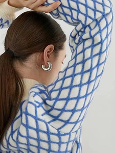 Gros plan de boucles d'oreilles créoles argentées en forme de C portées par un mannequin