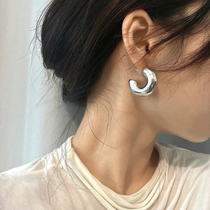 Gros plan de boucles d'oreilles créoles en C argentées épaisses avec fini poli miroir