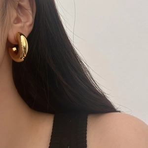Détail macro d'une boucle d'oreille dorée en forme de C avec finition miroir polie