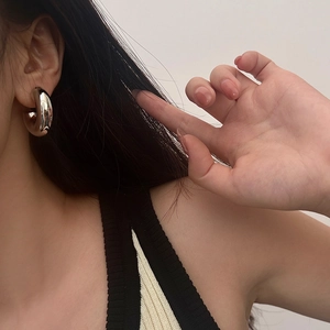 Gros plan d'une boucle d'oreille créole argentée épaisse avec fini poli miroir