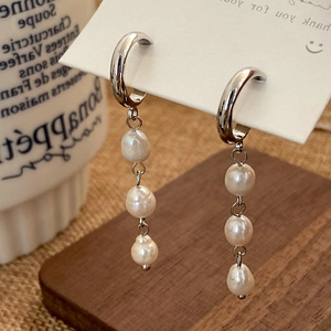 Detail of silver drop earrings featuring triple freshwater pearls on a white card