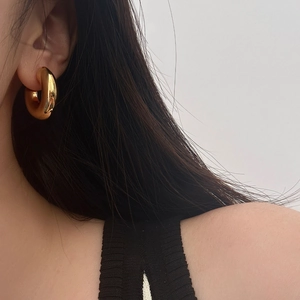 Gros plan de boucles d'oreilles créoles dorées en C avec une finition miroir polie