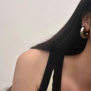 Gros plan d'un mannequin portant des boucles d'oreilles créoles épaisses en argent poli