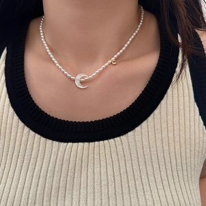 Détail d'un collier de perles élégant avec pendentif croissant sur le cou d'un mannequin