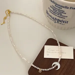 Détail du pendentif croissant de lune et collier de perles nacrées sur support en bois