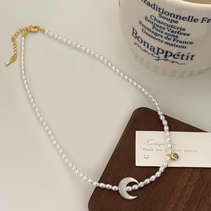 Détail du collier de perles avec pendentif croissant en nacre et fermoir doré élégant