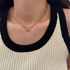 Close-up of champagne faceted glass beads with a polished gold ball pendant necklace