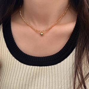 Champagne crystal beaded necklace with a gold spherical pendant on a model's collarbone
