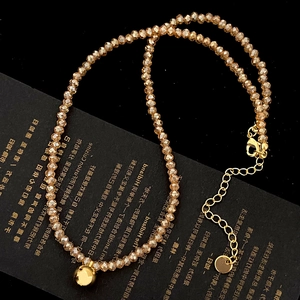 Detailed macro of amber faceted glass beads necklace with golden bell and lobster clasp