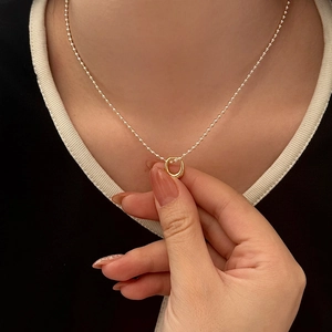 Detailed view of a minimalist gold ball chain necklace with a small circular ring pendant