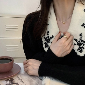 Close-up of elegant gold ring set and minimalist oval pendant necklace on model