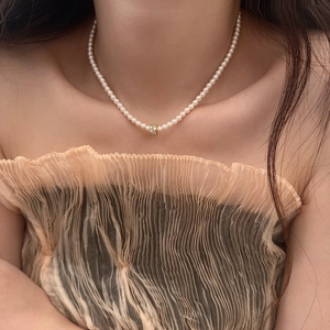 Détail d'un collier de perles blanches avec perle dorée sertie sur un décolleté élégant