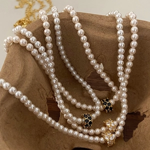 Collier de perles élégant avec charmes dorés et cristaux sur support rustique