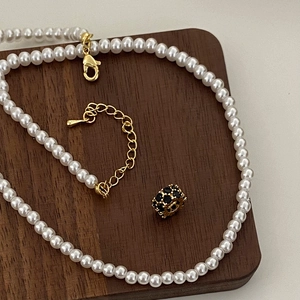 Détail d'un collier de perles blanches avec fermoir doré et perle de cristal noire