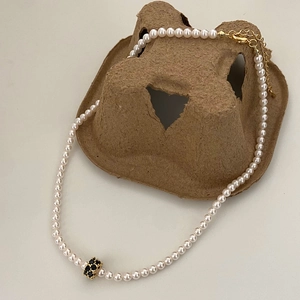 Détail du collier de perles avec pendentif en pierre noire et fermoir mousqueton doré