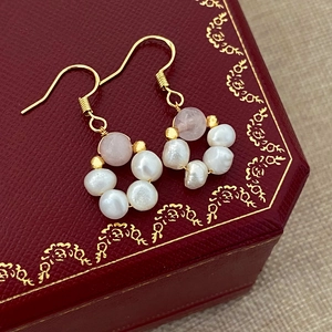 Macro shot of freshwater pearl earrings with pink gemstones on red luxury leather