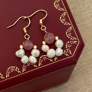 Detail view of baroque pearl earrings with pink crystal beads on red jewelry box