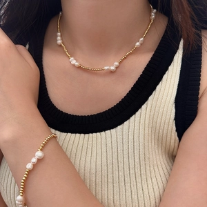 Elegant freshwater pearl necklace and bracelet set with golden beads on a female model