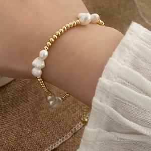 Detailed shot of baroque pearls and gold beads bracelet on a female wrist
