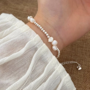 Close-up of baroque pearl bracelet with silver beads and heart pendant on wrist