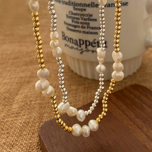 French elegant baroque pearl necklace with gold and silver beads on a brown table