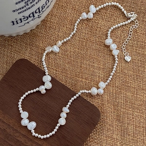 Detailed macro view of baroque pearl necklace with silver beads and heart charm
