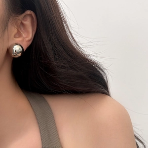 Close-up of a high-polished silver ball earring showing a sleek mirror finish on a model