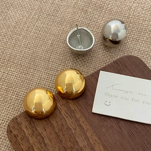 Polished gold and silver ball stud earrings set shown on a wooden display base