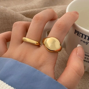 Close-up of a two-piece minimalist gold rings set on a model hand with home decor