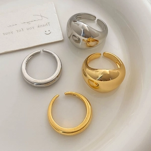 Minimalist thick dome open rings in gold and silver finish on a ceramic plate