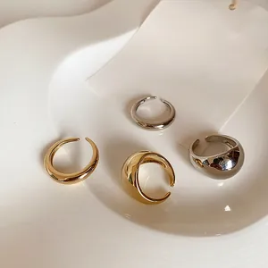 Macro view of four minimalist polished open rings in gold and silver finish on white tray