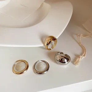 Polished gold and silver adjustable open rings displayed on a minimalist white tray