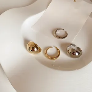 Detailed view of glossy gold and silver chunky dome rings on a ceramic display tray