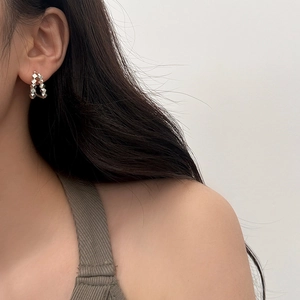 Close-up of double-layered silver metallic geometric hoop earrings on female ear