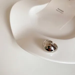 Close-up of polished silver wide dome open ring on a minimalist white ceramic tray