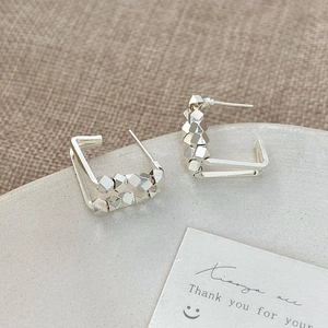 Minimalist silver geometric hoop earrings with faceted metal beads on stone display